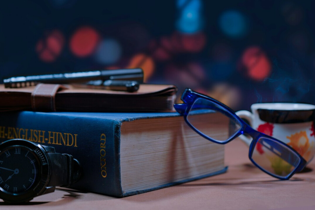 Stack of documents with a calculator and reading glasses on a table